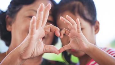  grandmother and little child girl making heart shape with hands together with love