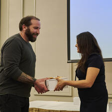 Trustee Kanda-Rajwan shakes hand with male employee receiving gift for long term service