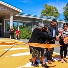 3 adults and 1 students cut the ribbon